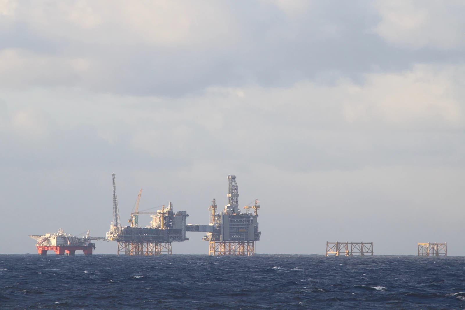 Several North Sea oil platforms visible on the open water under a gray sky.