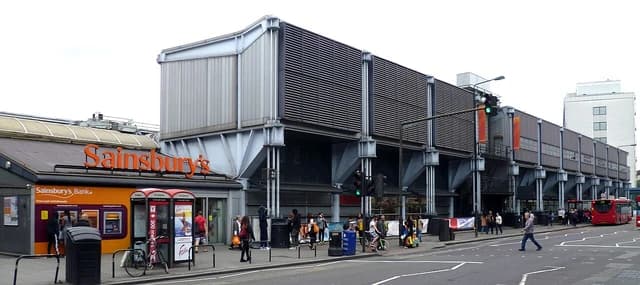 Exterior view of J. Sainsbury's supermarket building on Camden Road, London, with people outside.