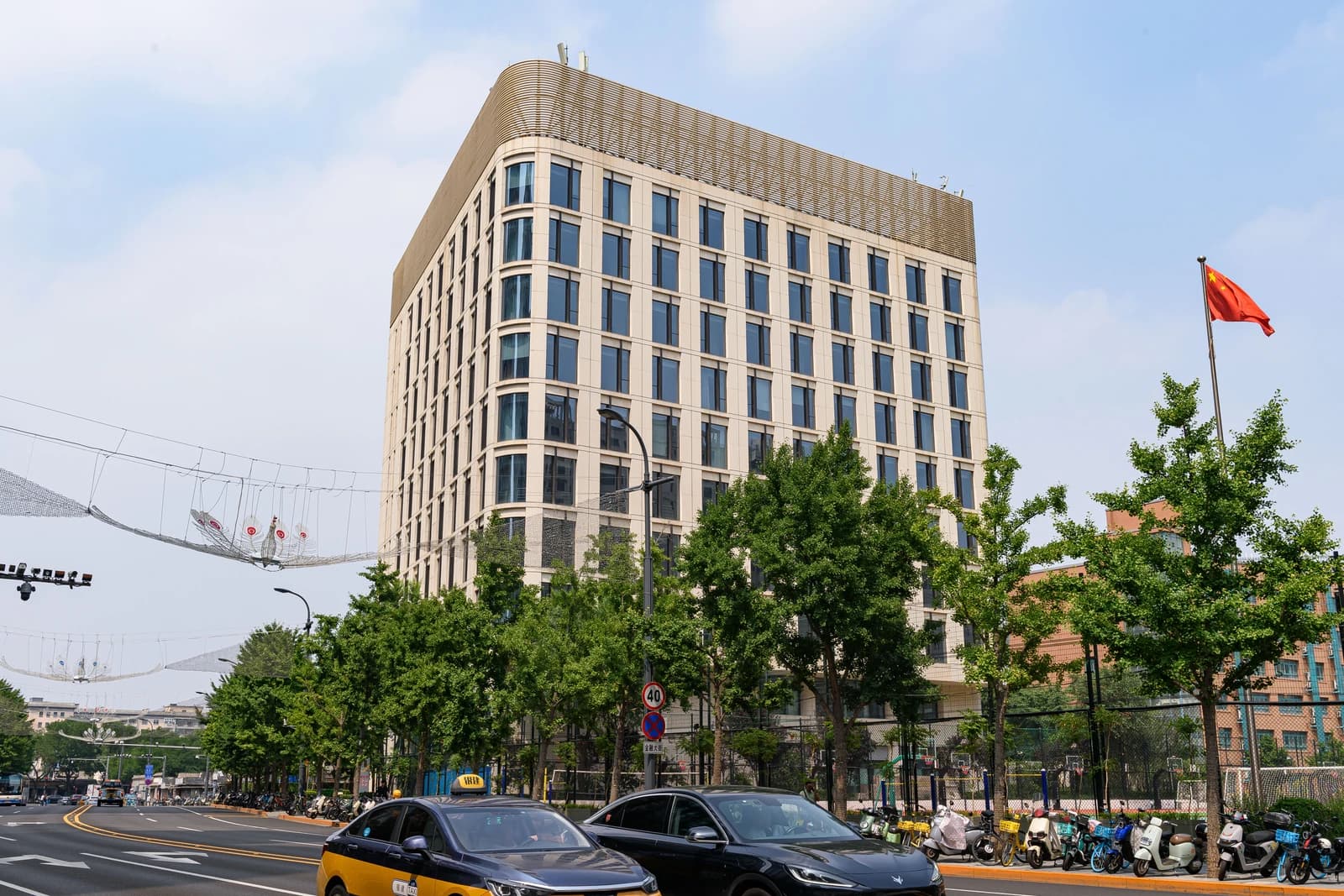 Jinyi Building, a large light-colored building with many windows, viewed from the street.