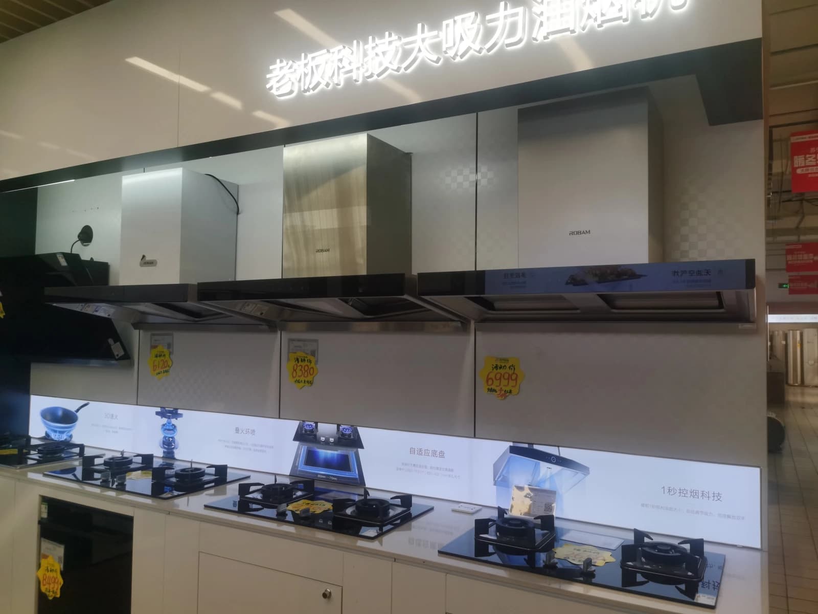 Robam kitchen hoods and stovetops on display in a retail showroom.