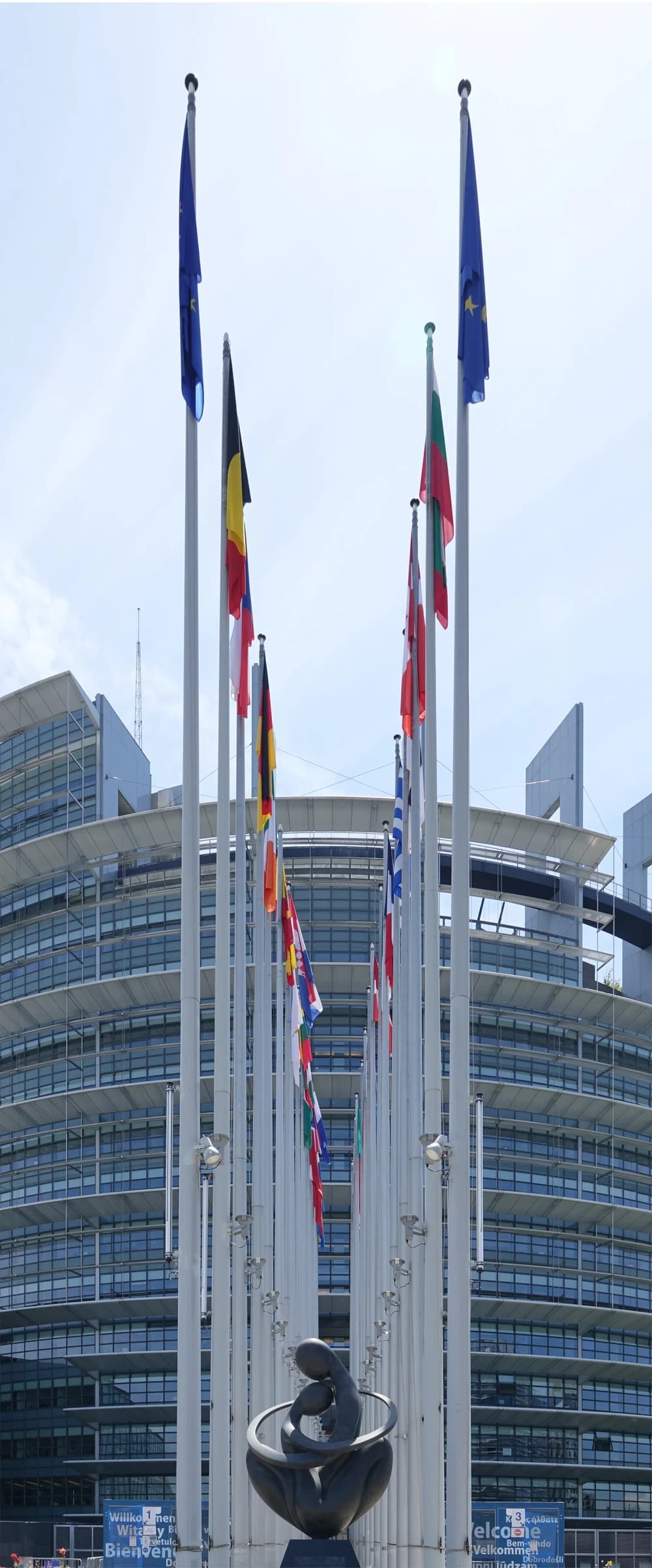 Exterior of the European Parliament in Strasbourg with European Union and national flags flying.