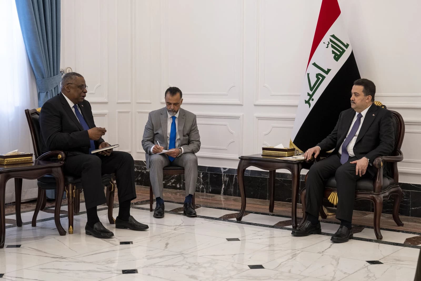 U.S. Secretary of Defense Lloyd Austin and Iraqi Prime Minister Mohammed Shia’ Al-Sudani sit in chairs at a meeting.