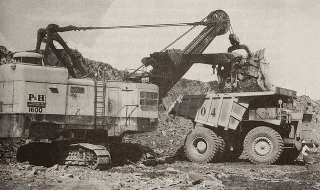 Steam shovel loading copper and cobalt ore into a large truck at Musonoi Mine.