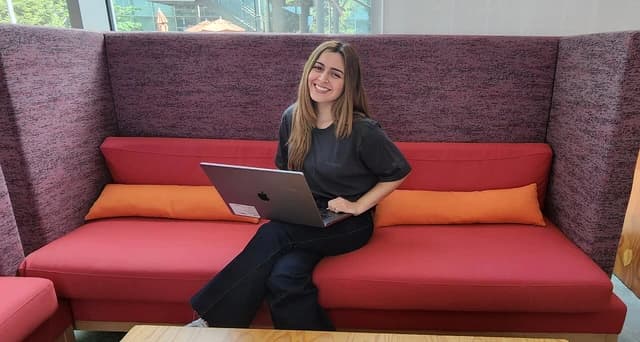 Diana Vicezar, Meta Product Design, smiling while sitting with laptop.