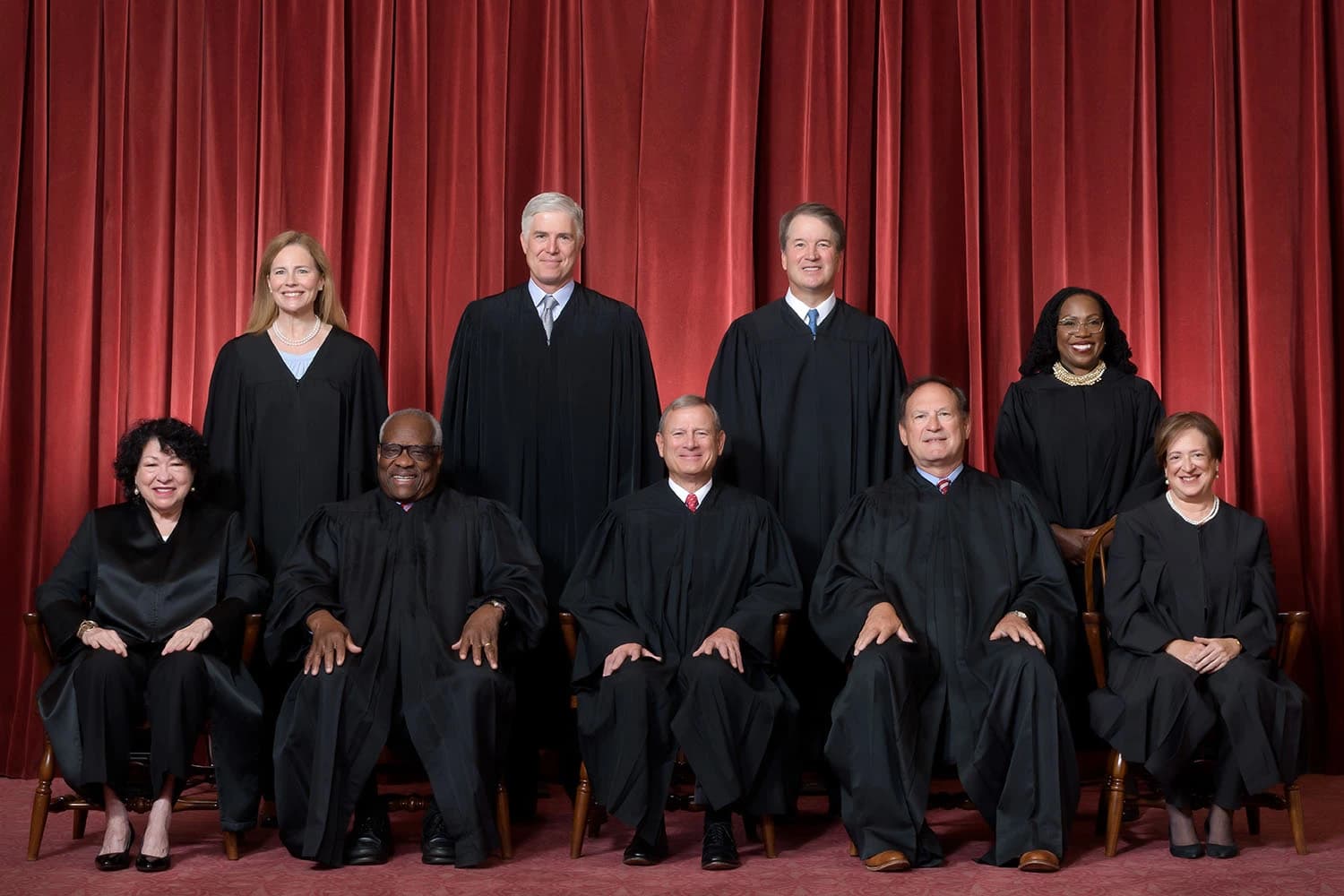 Nine Supreme Court justices, four seated and five standing, pose for an official portrait.
