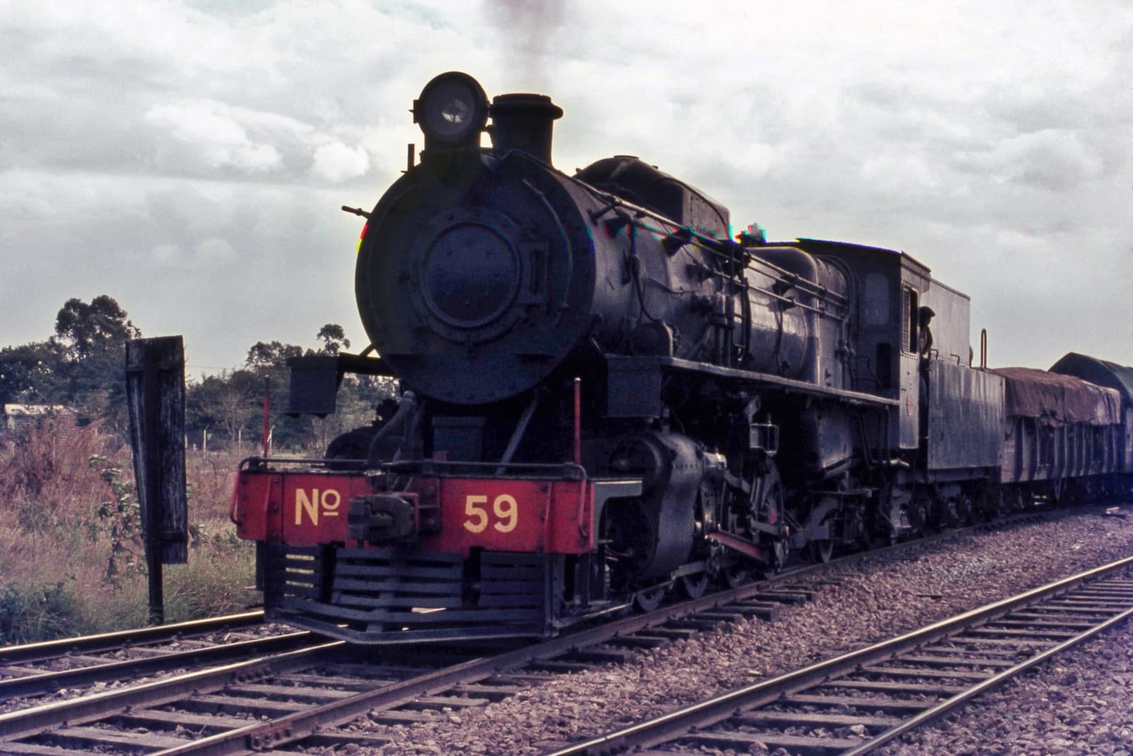 Steam locomotive 'Nº 59' with freight cars on tracks in Mozambique.