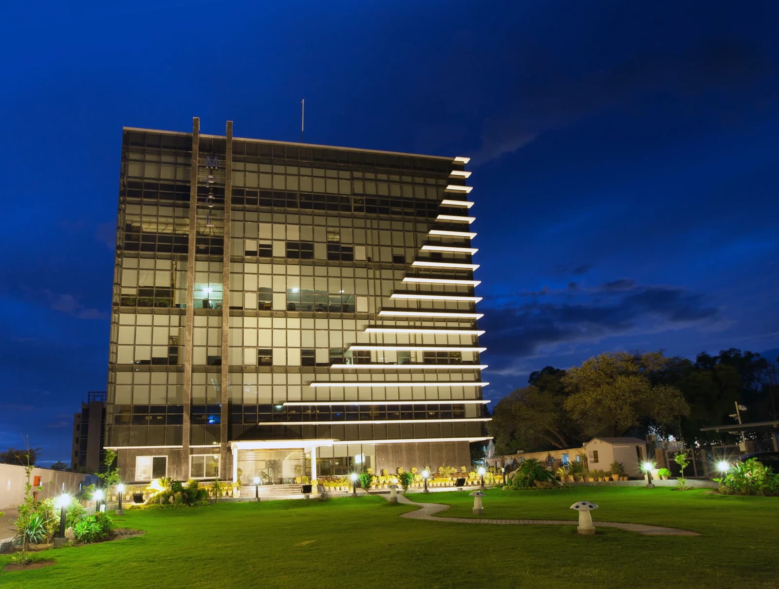 Mari Petroleum Head Office building exterior with illuminated facade and manicured lawn at night.