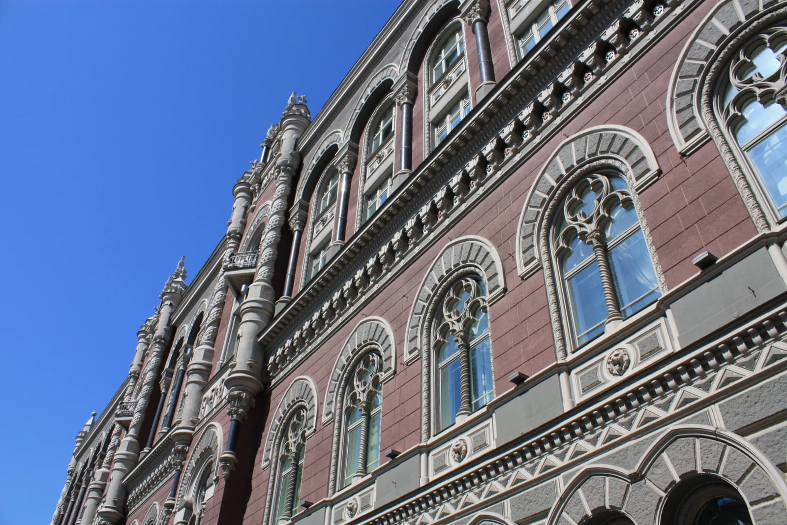 The ornate facade of the National Bank building in Kyiv under a bright blue sky.