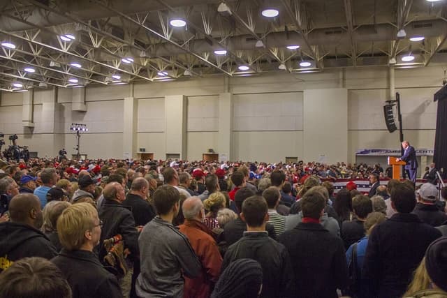 Donald Trump, former President of the United States, speaking at a podium to a large audience.