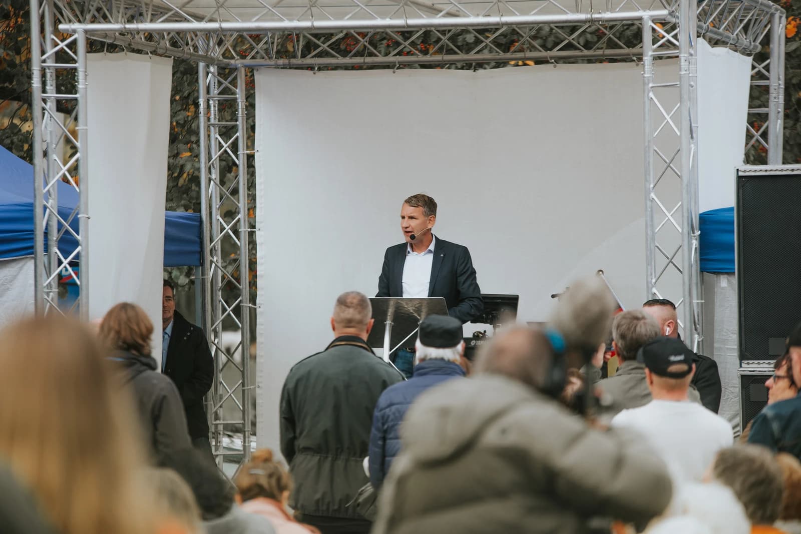 Björn Höcke, AfD politician, speaks from a podium to an audience outdoors.