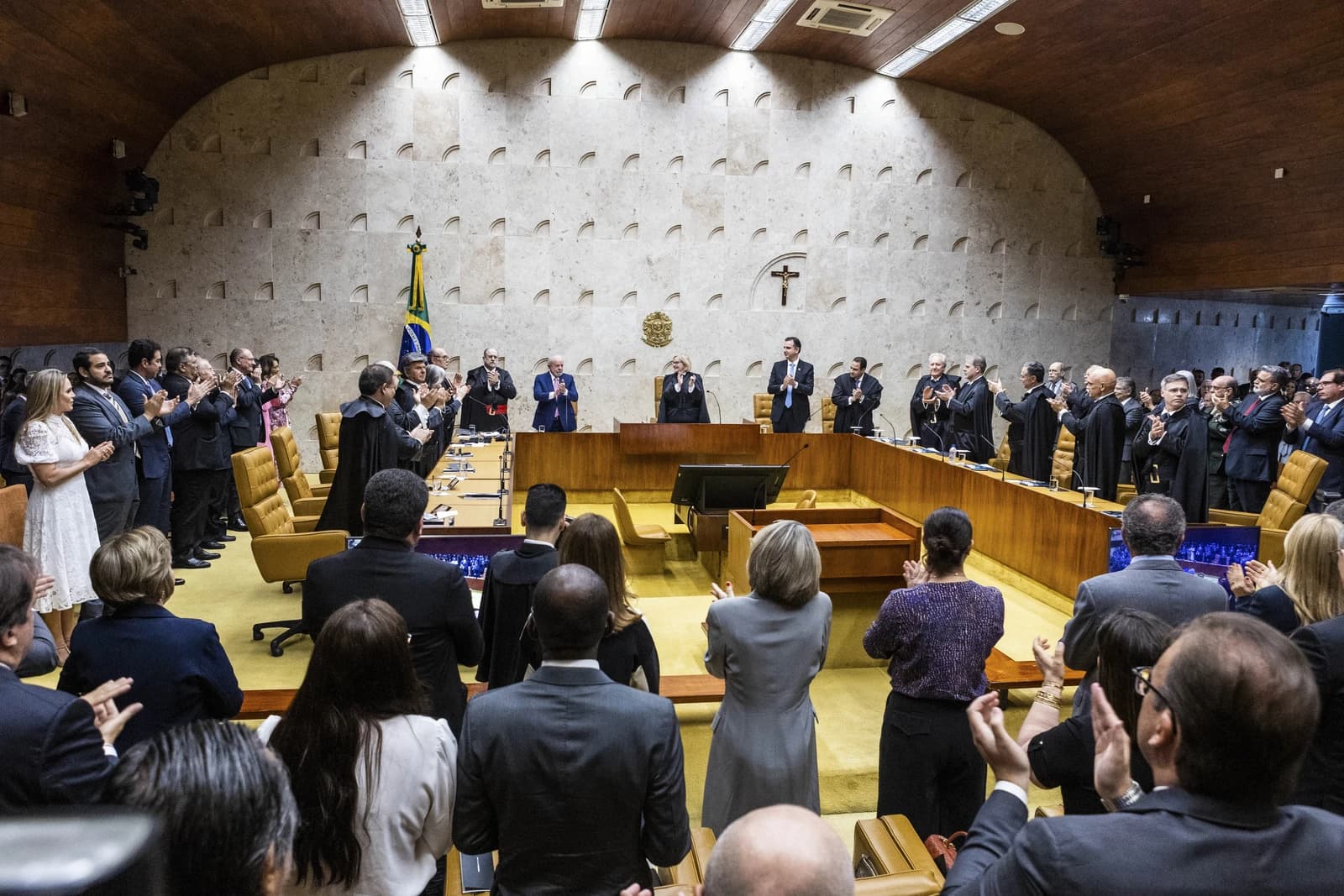 Brazilian Supreme Court justices and other individuals standing and applauding in a courtroom.