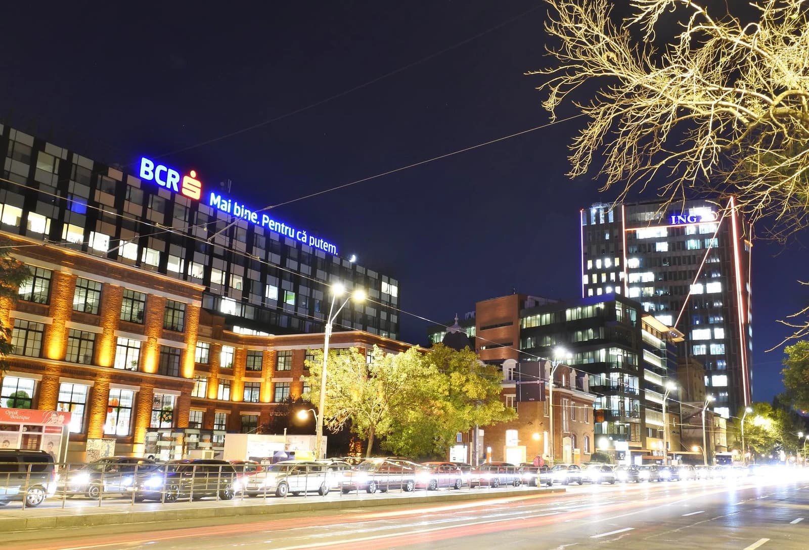Buildings lit up at night along a busy street in Bucharest, Romania.