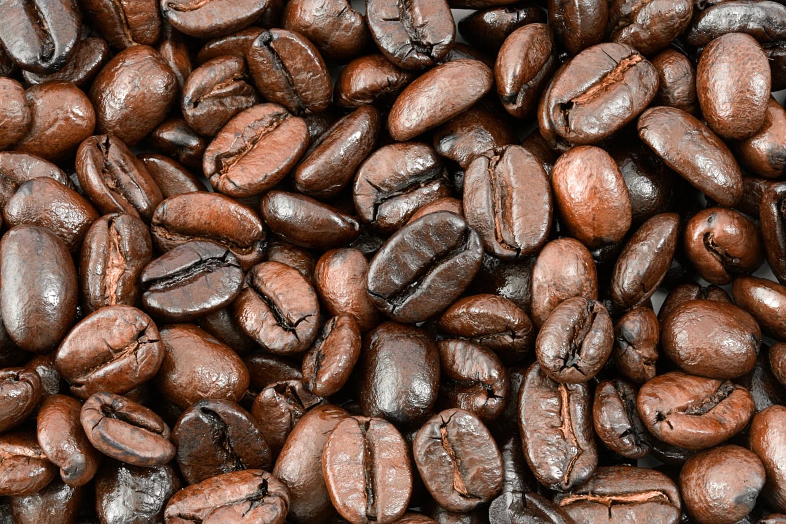 Close-up of roasted coffee beans, showing their texture and varied dark brown colors.