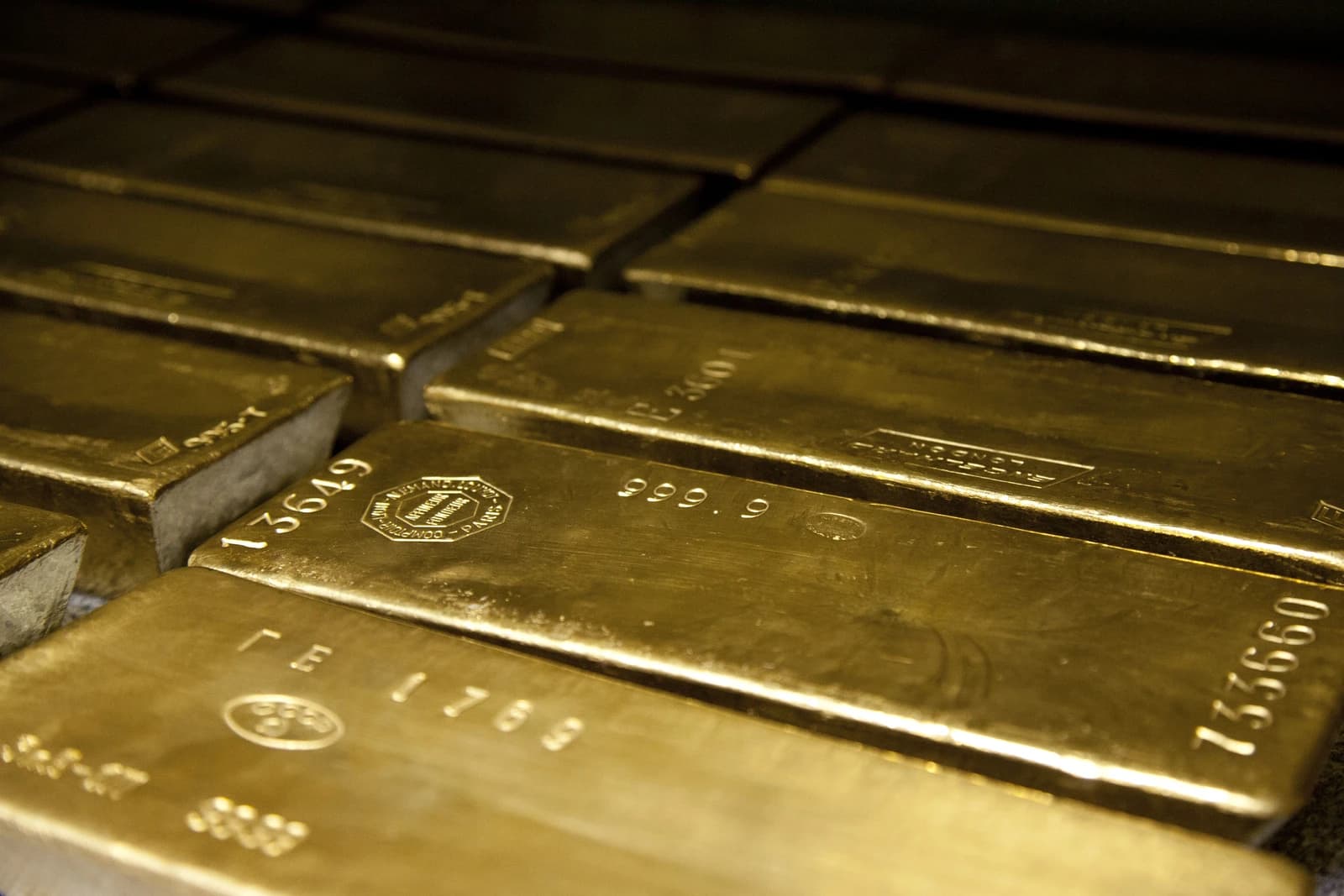 Several shiny 400-ounce gold bars with identifying stamps on their surfaces.