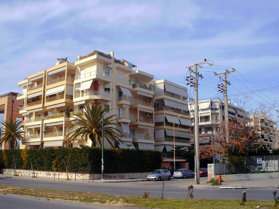 Apartment blocks in Moschato, Greece, with cars parked along the street.