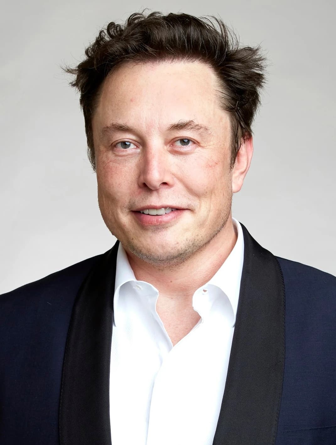 Elon Musk, CEO of Tesla and SpaceX, smiling in a formal portrait.