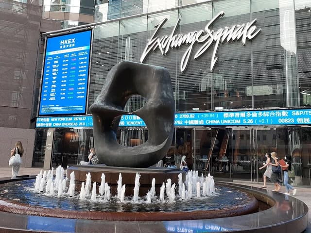 Exterior view of Exchange Square in Hong Kong, featuring a large digital display showing stock information.