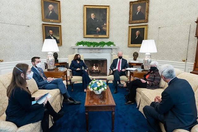 President Joe Biden and Treasury Secretary Janet Yellen meeting with others in a room.