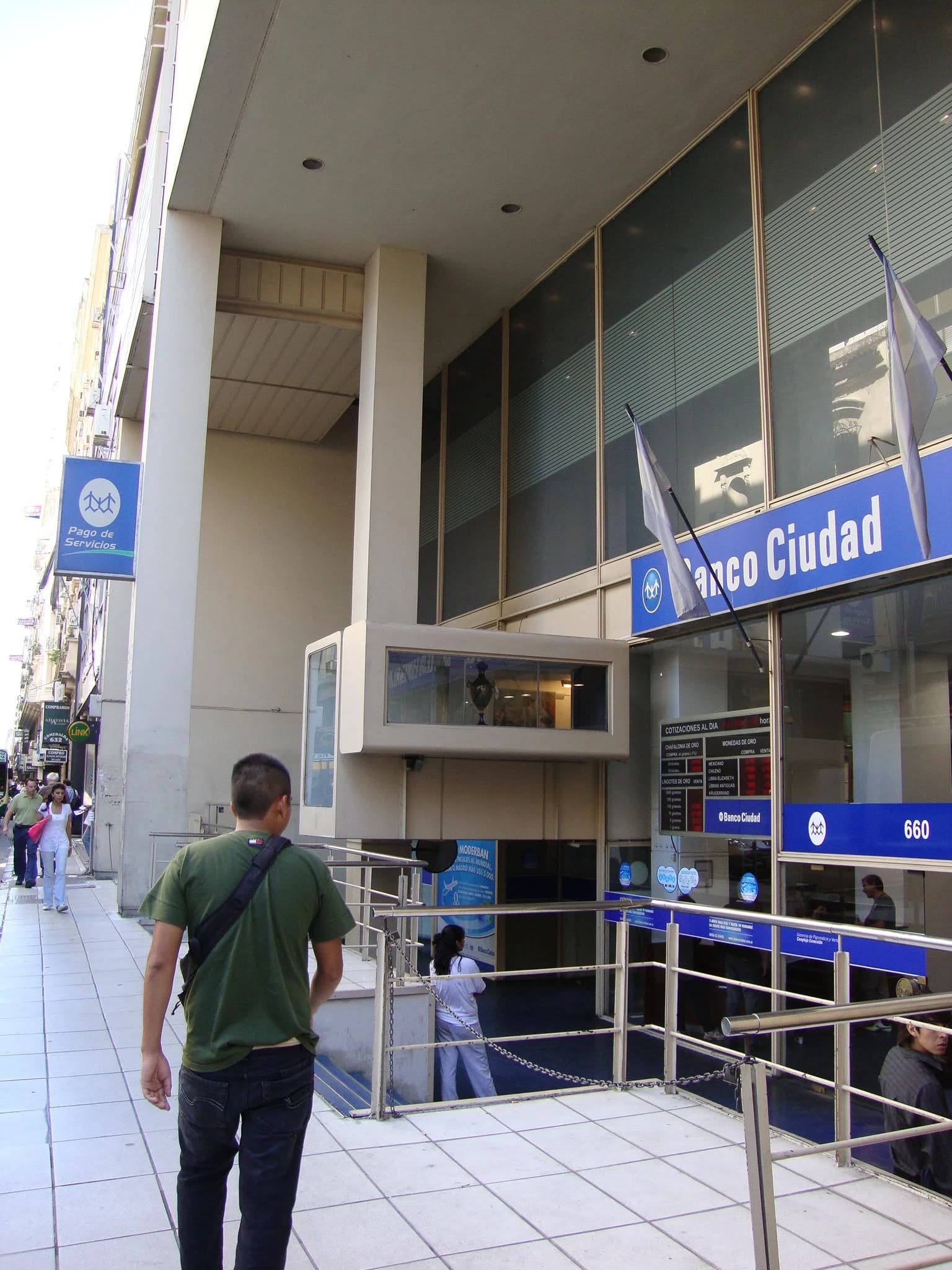 Pedestrians walk past the street-level entrance of a Banco Ciudad branch building in Buenos Aires.