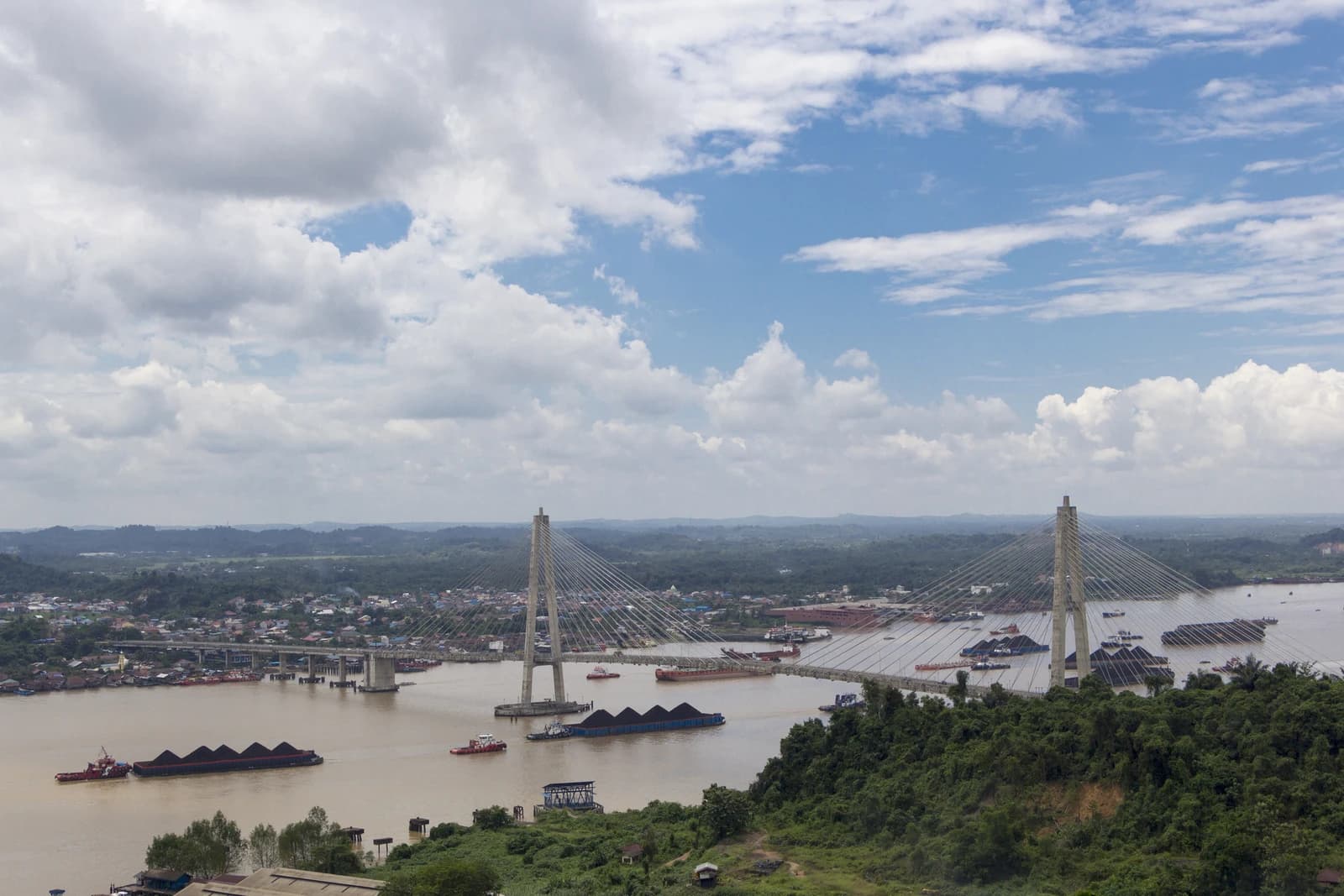 Coal barges on Mahakam River under Mahkota 2 Bridge in Samarinda, Indonesia.