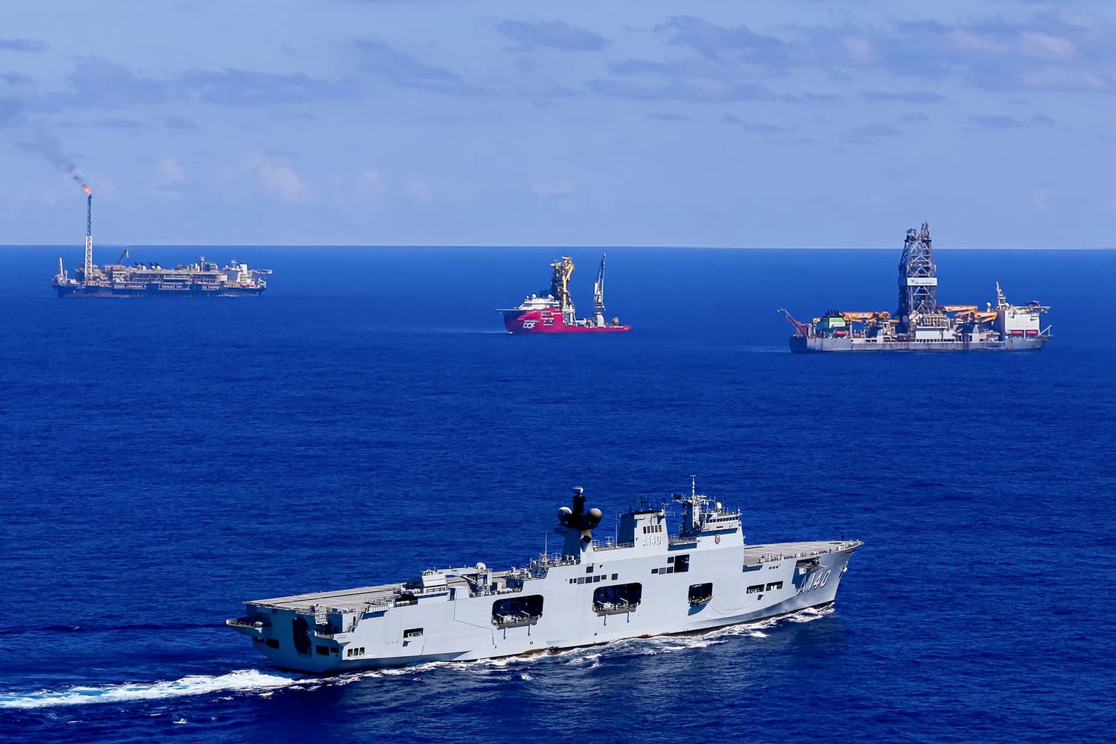 Brazilian Navy multipurpose aircraft carrier Atlântico (A140) sails past oil platforms offshore.