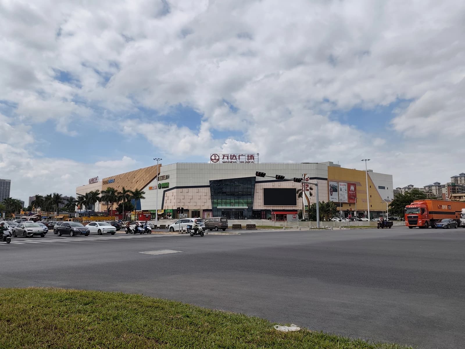 Wanda Mall in Xinhui, China, with cars and motorcycles on the street in front.