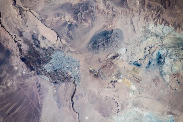 Aerial view of the vast Chuquicamata copper mine, a large open-pit mine in a desert region.