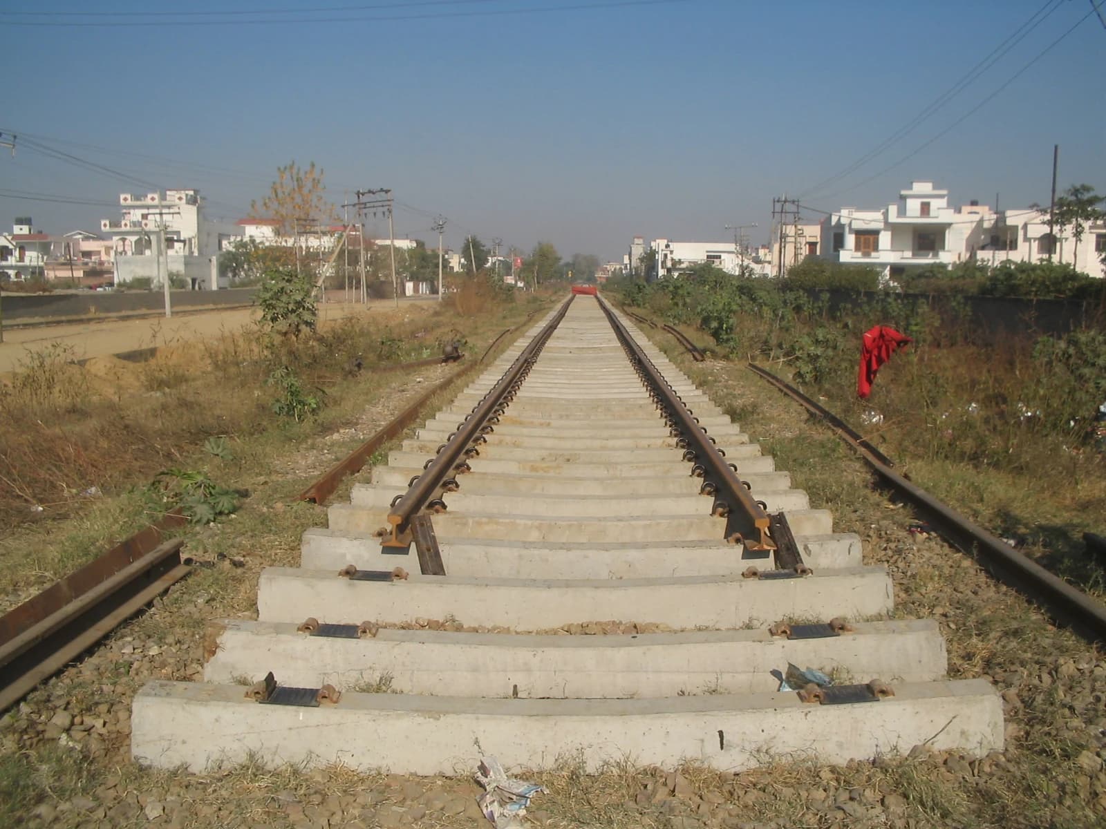 New railway tracks being laid with concrete sleepers stretching into the distance.