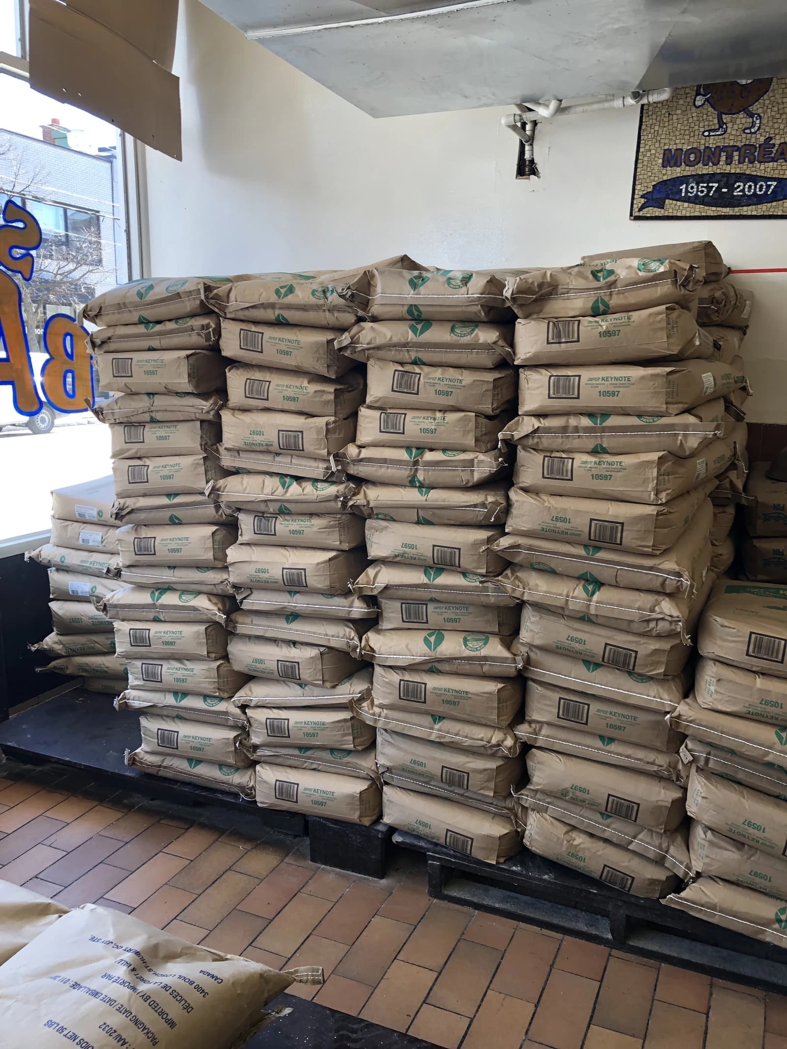 Stacks of large flour bags piled on wooden pallets inside a commercial building.
