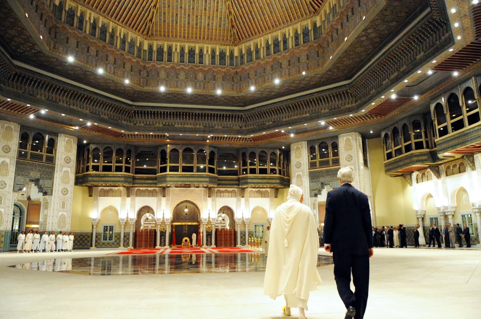 King Mohammed VI and a guest walking through the ornate interior of a palace.