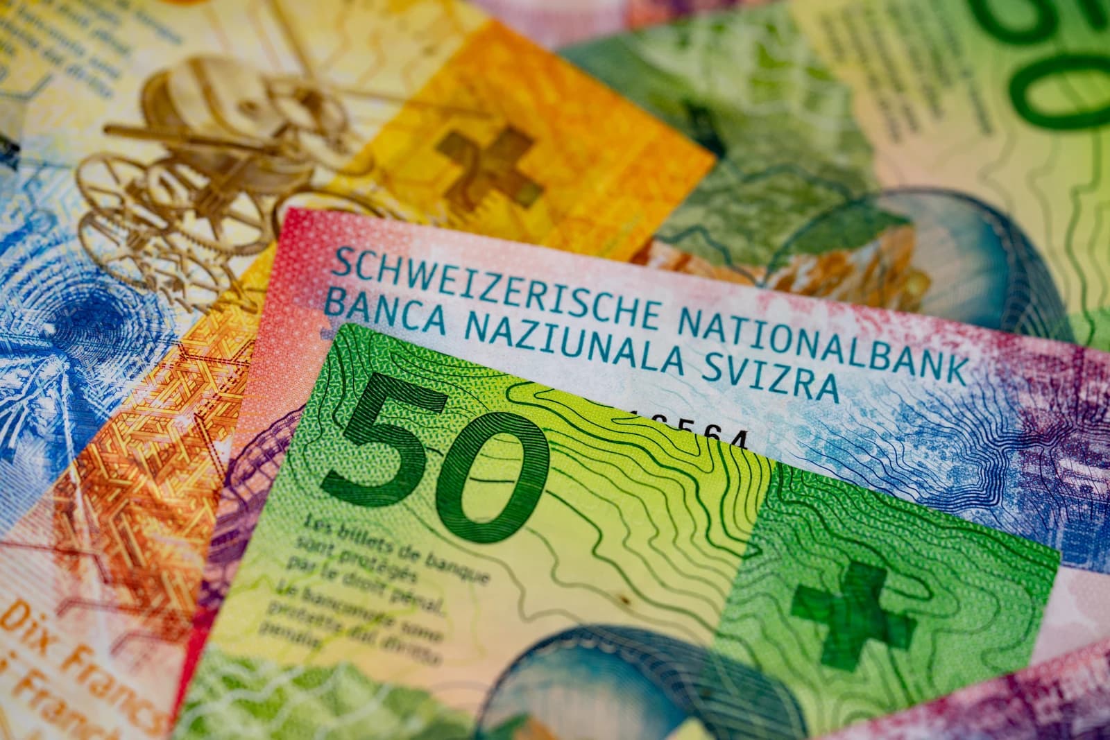 Close-up of scattered Swiss Franc banknotes, including a green fifty franc note.