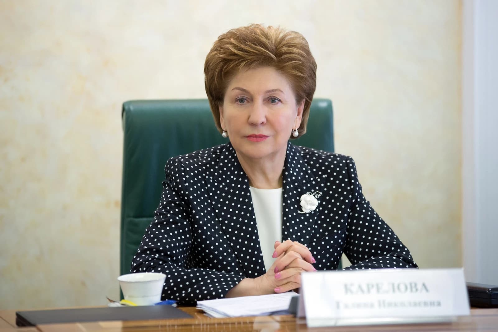 Galina Karelova, Russian politician, seated at a table with a nameplate.