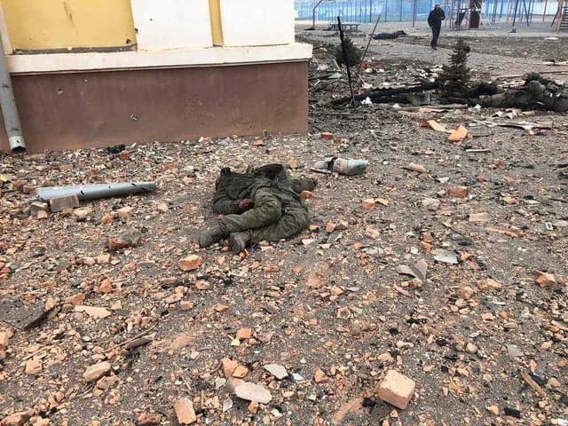 Bodies of deceased Russian soldiers lie on debris-strewn ground near a building.