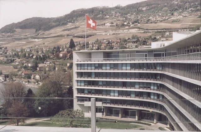 The Nestlé Headquarters building in Vevey, Switzerland, with a Swiss flag on the roof.