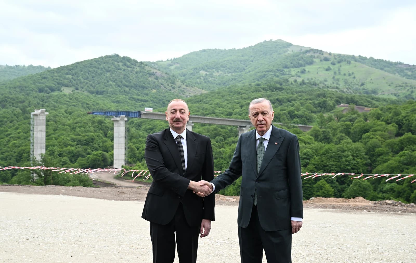 Ilham Aliyev, President of Azerbaijan, and Recep Tayyip Erdoğan, President of Türkiye, shake hands at a highway construction site.