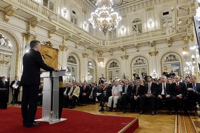 Mauricio Macri, then-President of Argentina, speaks at a podium to an audience.