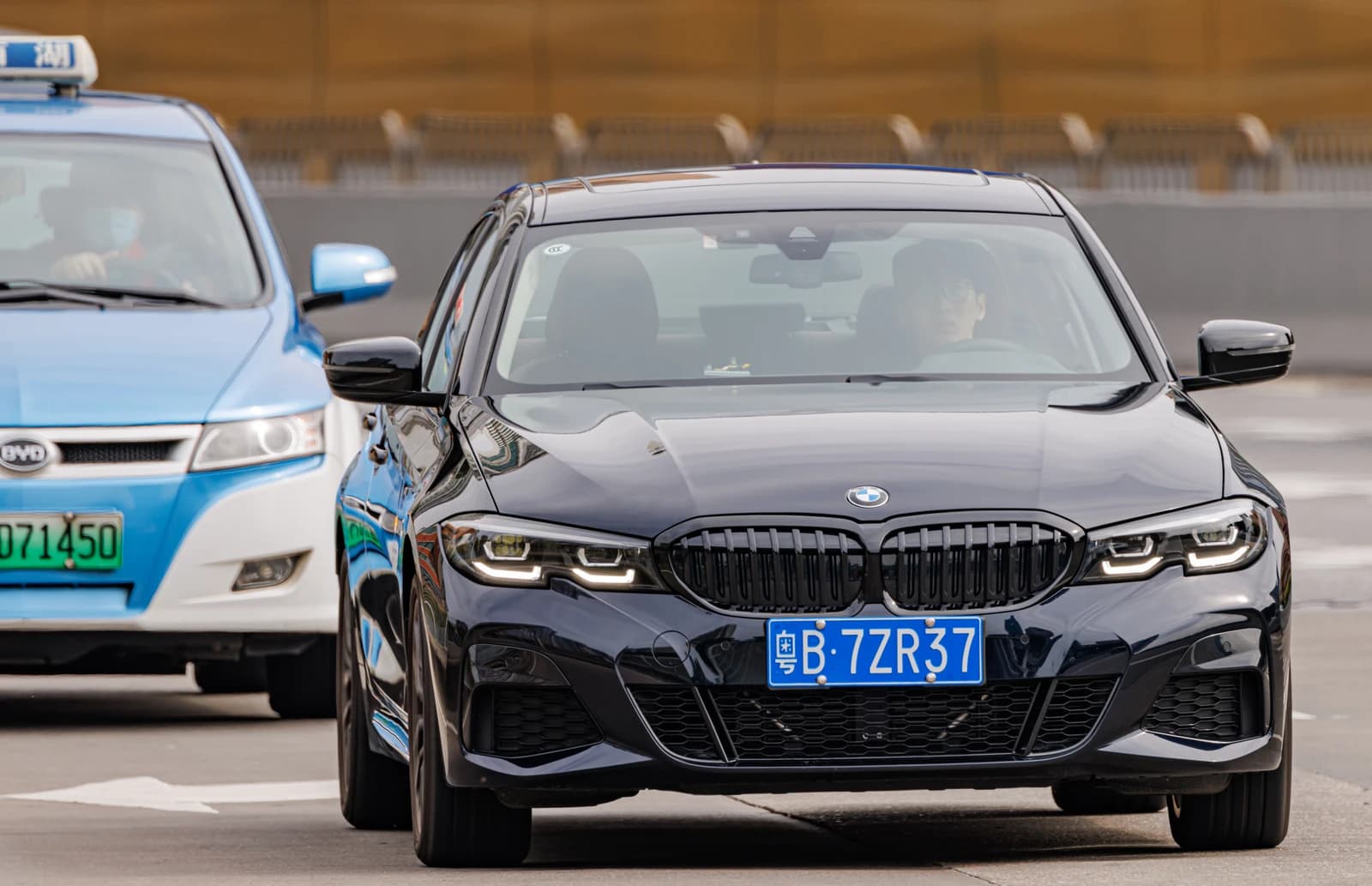 Dark blue BMW 3 Series sedan driving on a city street in China.