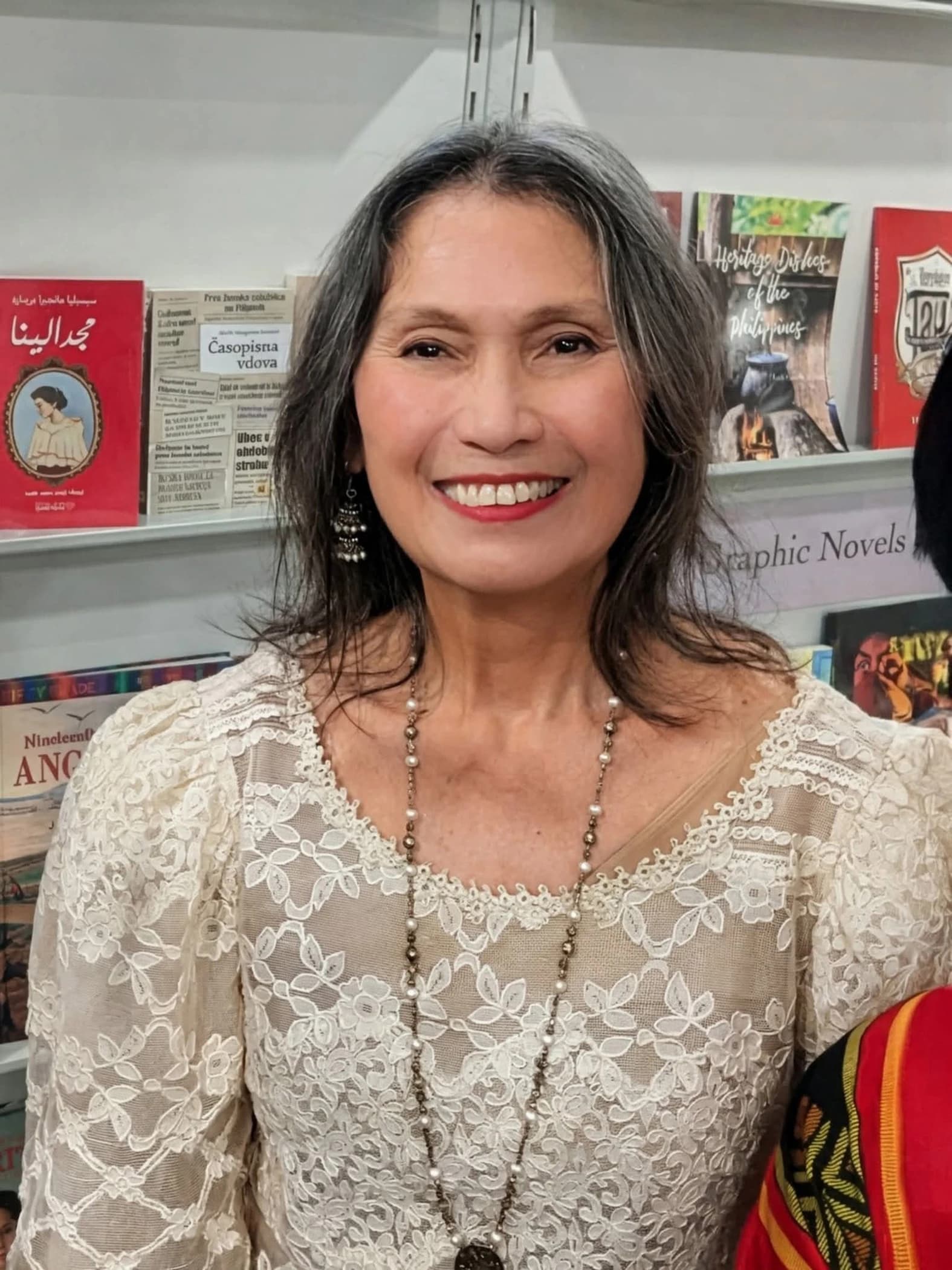 Cecilia Brainard smiling at the Frankfurt Book Fair in front of bookshelves.