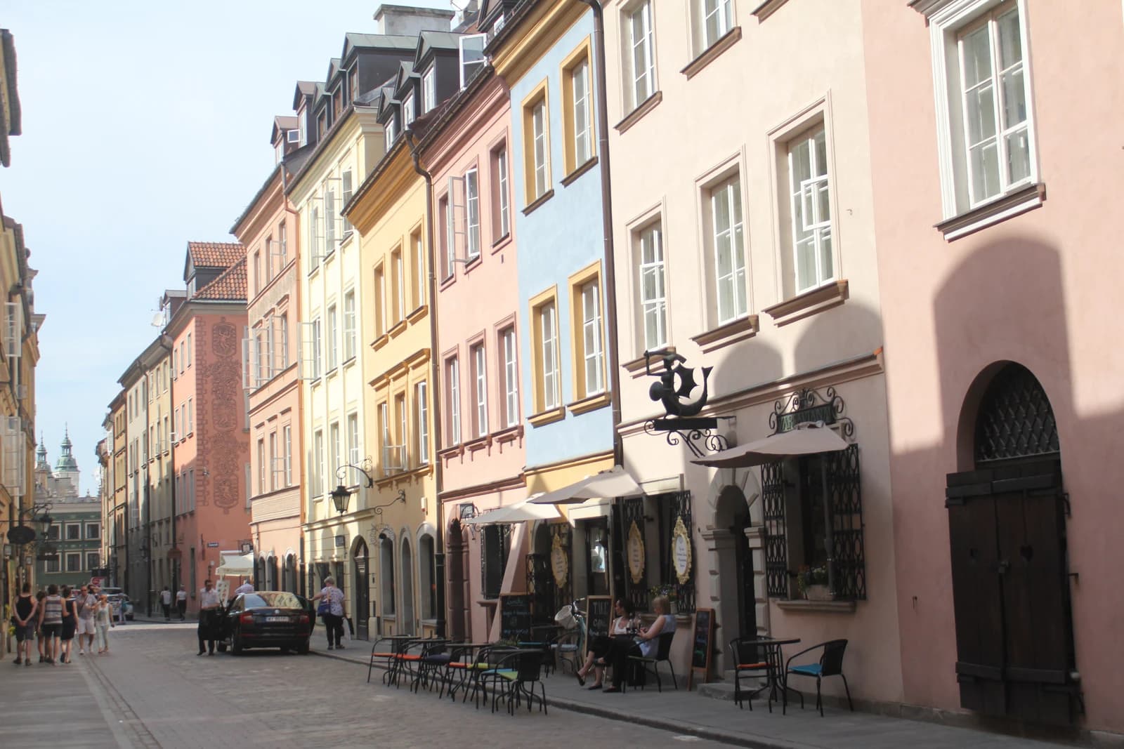 A cobblestone street in Krakow's Old Town with colorful buildings and outdoor cafes.