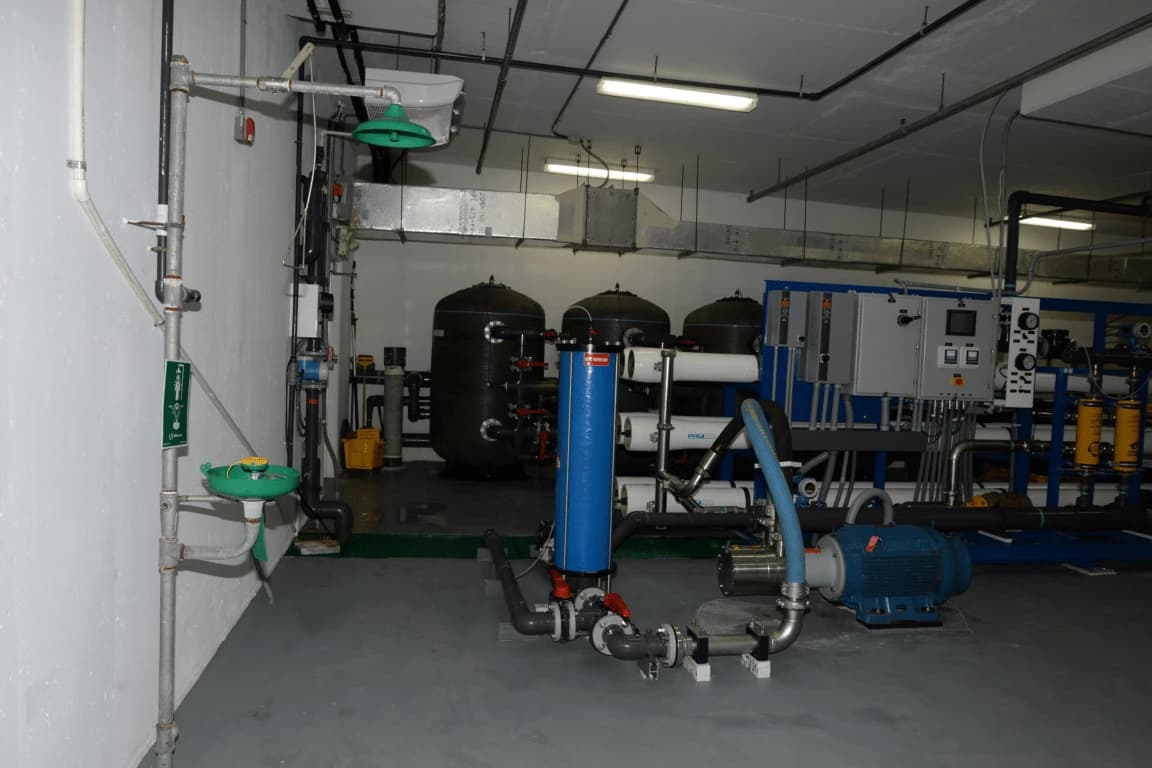 Industrial water treatment room with large tanks, pipes, pumps, and control panels.