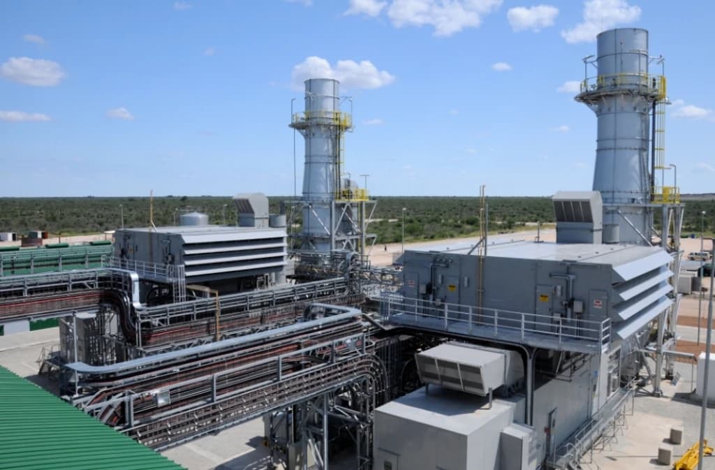 An outdoor gas turbine power plant with multiple industrial structures and smokestacks.