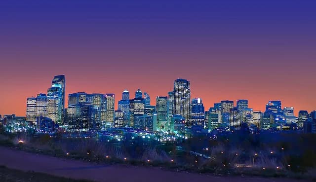 Skyline of Calgary, Alberta, Canada at dusk with city lights visible.