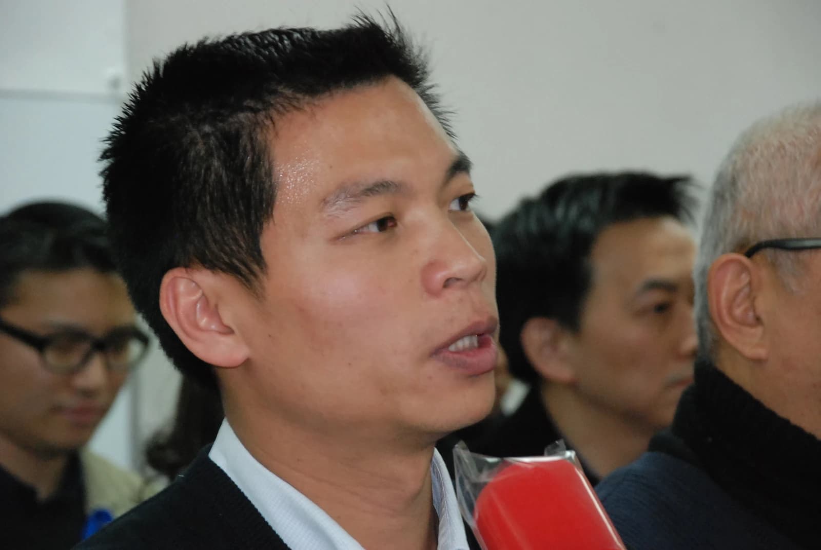 Bruce Lui, a Hong Kong journalist, speaks into a red microphone.