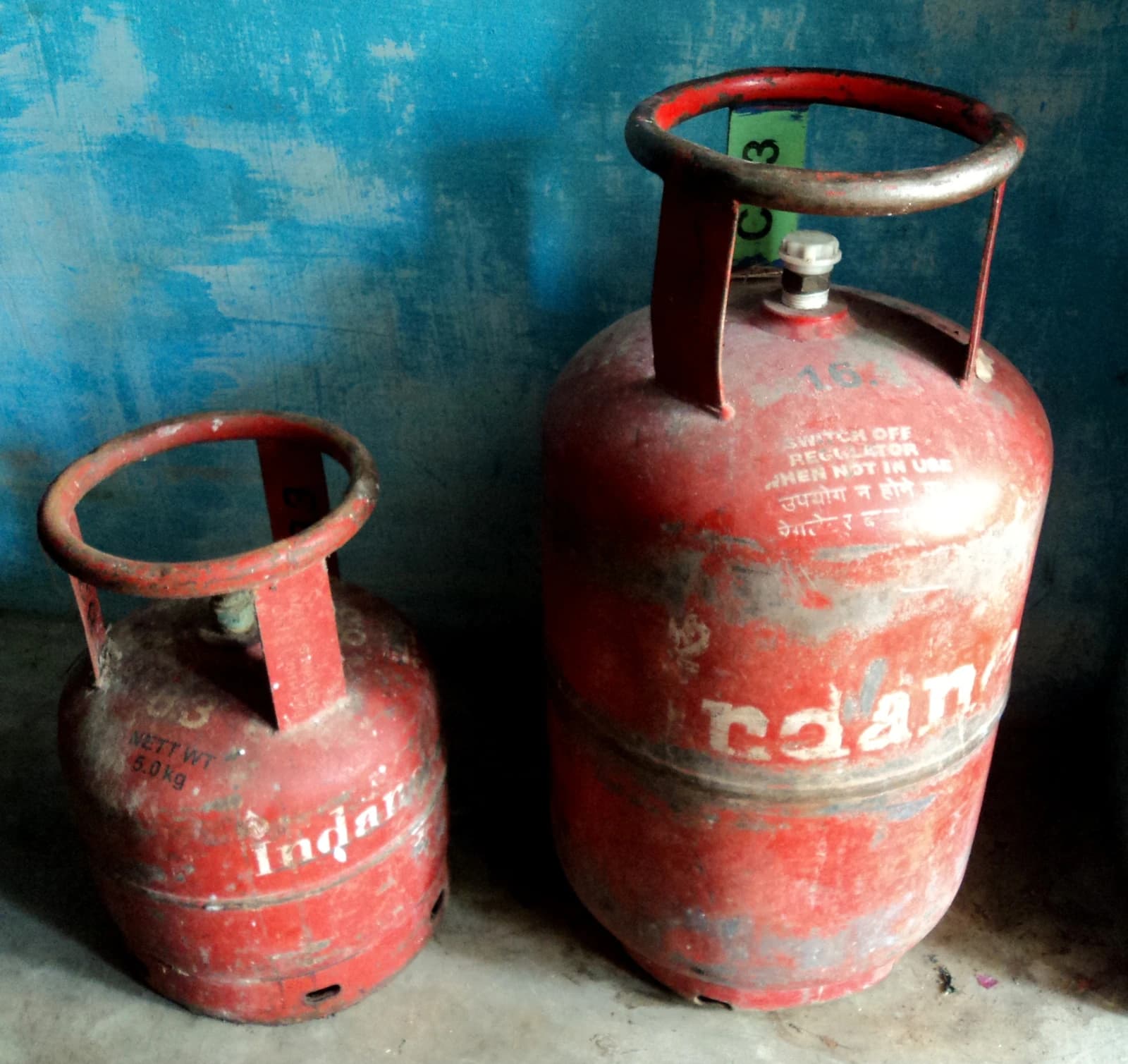 Two red Indane brand gas cylinders standing upright against a blue background.