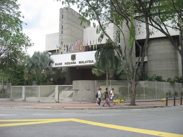 Exterior of Bank Negara Malaysia building, with pedestrians walking on the sidewalk.
