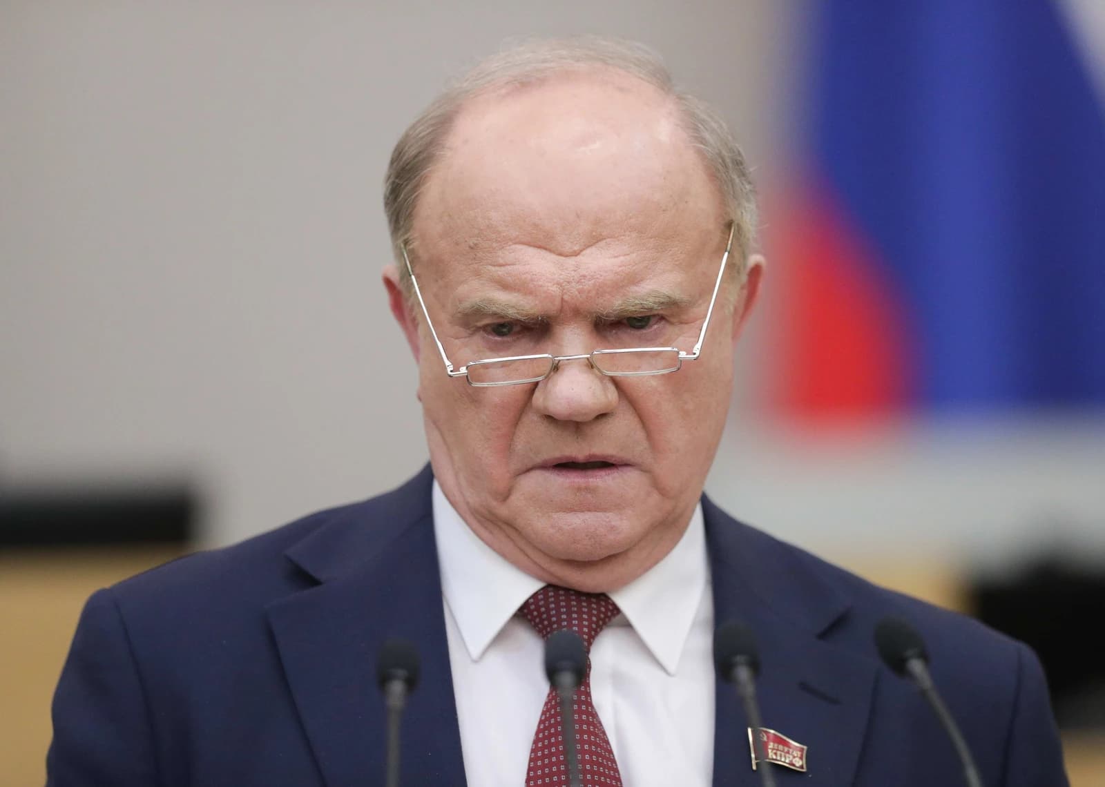Gennady Zyuganov, leader of the Communist Party, speaks at a podium with microphones.