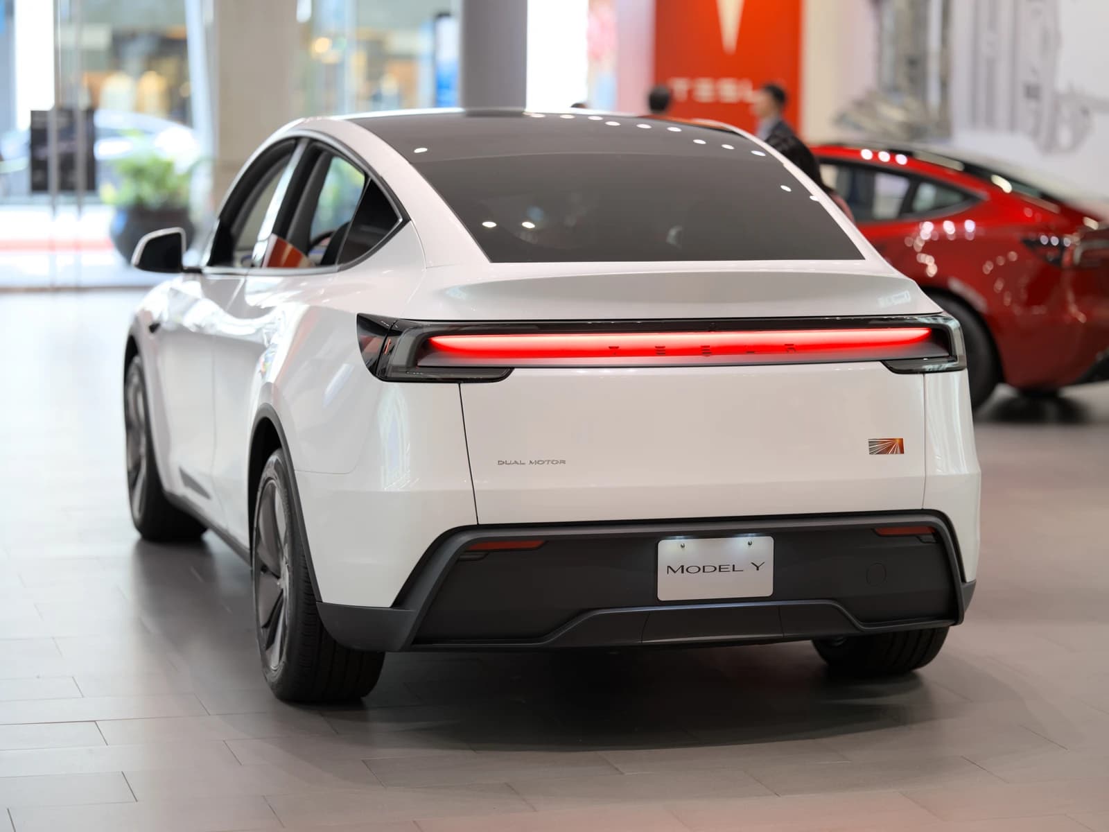 White Tesla Model Y car displayed indoors, rear view.