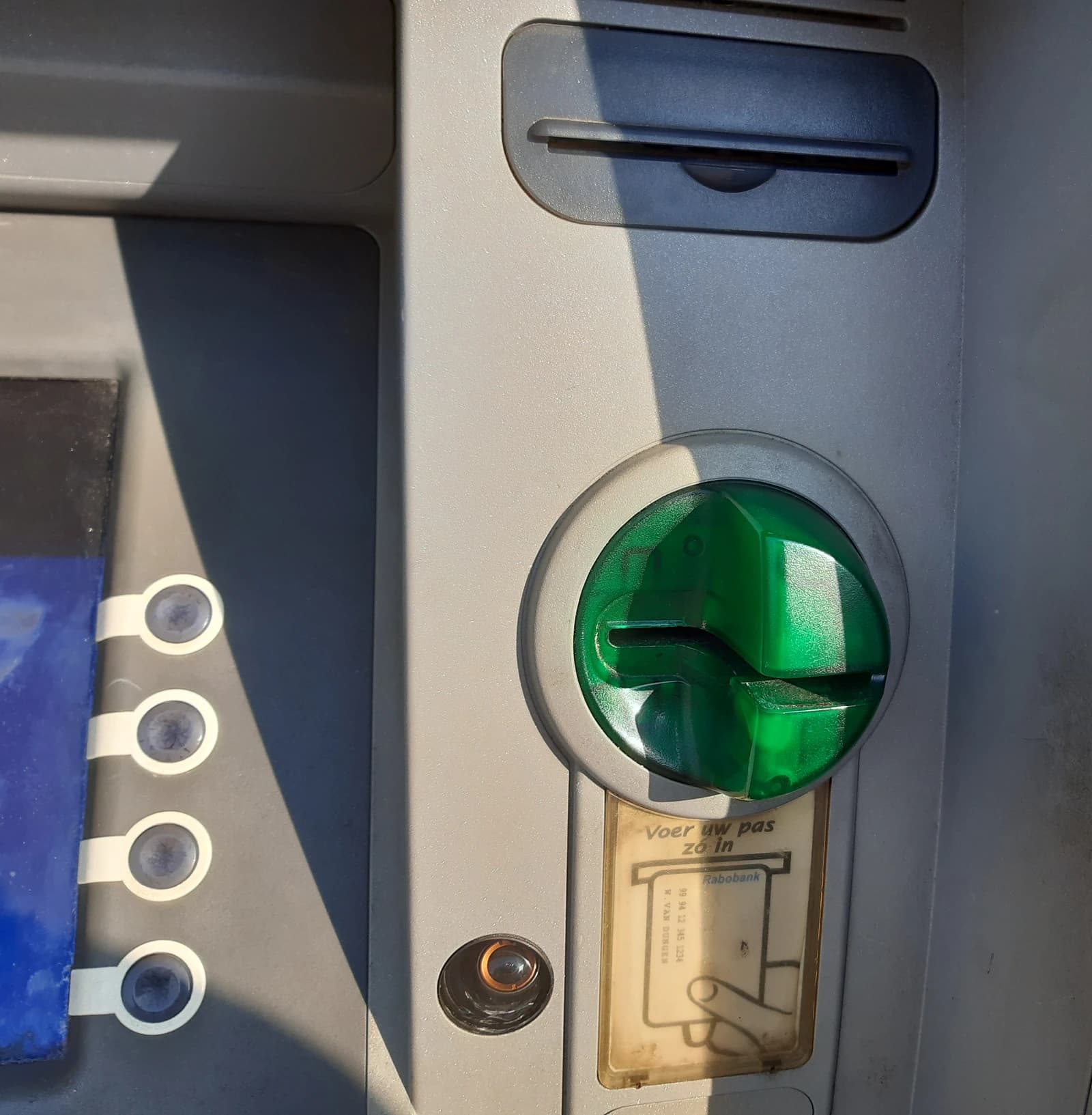 Close-up of a green card slot on an ATM, designed to prevent skimming.
