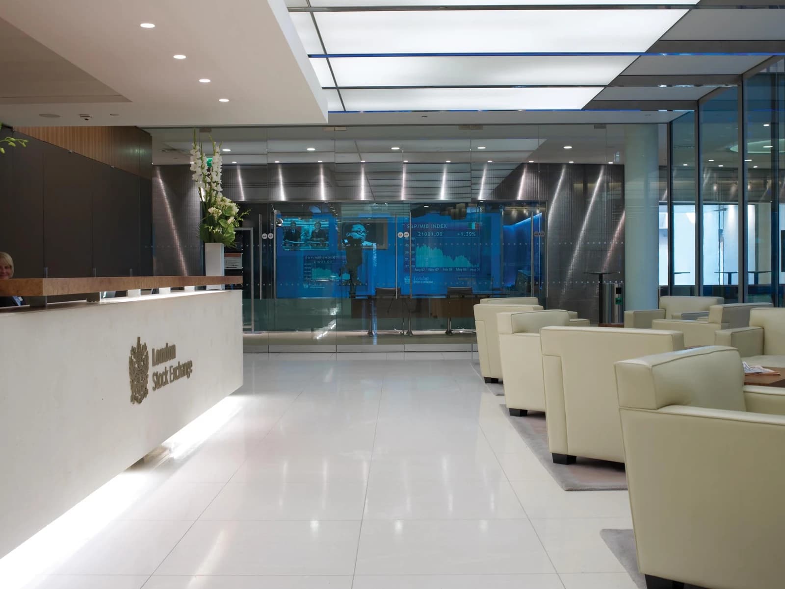 Reception desk inside the London Stock Exchange building with a large display screen in the background.