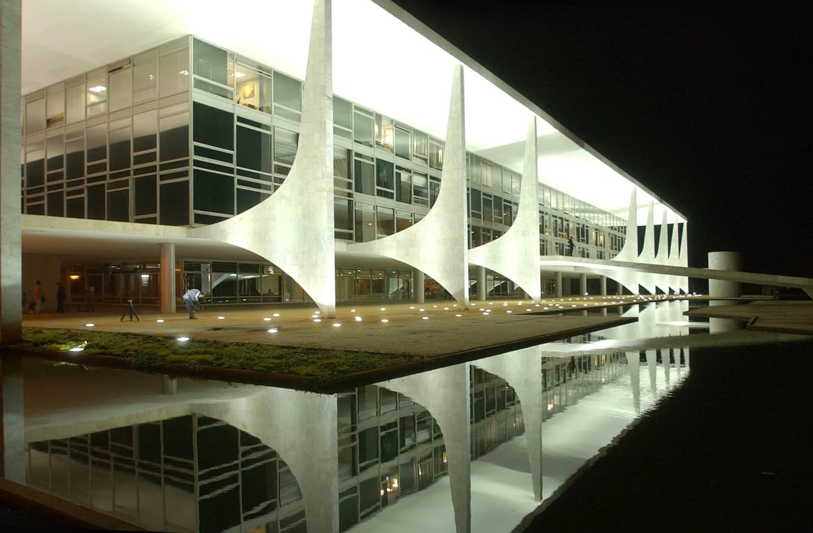 Palácio do Planalto, illuminated at night, with its reflection visible in a pool of water.